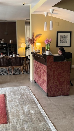 A reception area with a patterned desk, a chair, a lamp, and a framed picture on the wall. - Hotel Vanilla (Timisoara)