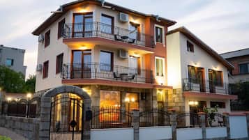 Un edificio residencial de varios pisos con balcones, una puerta de entrada de piedra e iluminación en la fachada.