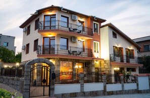 Un edificio residencial de varios pisos con balcones, una puerta de entrada de piedra e iluminación en la fachada.