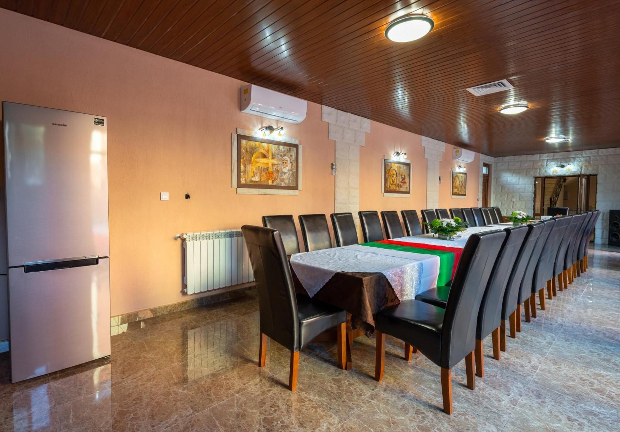 A conference room with a long table, chairs, a refrigerator, and wall-mounted air conditioning units.