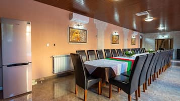 A conference room with a long table, chairs, a refrigerator, and wall-mounted air conditioning units.