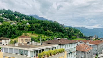Ein Wohngebiet mit Häusern, einem Hügel mit Grünflächen und einer in der Ferne sichtbaren, schlossähnlichen Struktur.