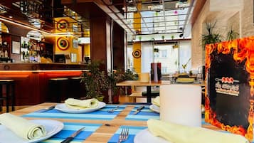 Ein Restaurant mit Barbereich, gedeckten Tischen und einer Wand mit Feuer-Motiv.