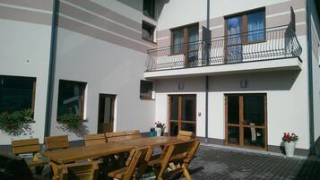 A two-story building with a balcony, wooden furniture, and potted plants.