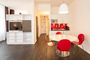 Una cocina moderna con microondas, cafetera y sillas rojas alrededor de una mesa blanca.