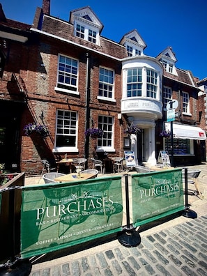 A brick building with a corner shop and a sign for 'PURCHASES' offering a bar, restaurant, and accommodation. - Purchases Restaurant Accommodation (Chichester)