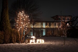 Un paysage enneigé, avec un arbre décoré de guirlandes lumineuses et une sculpture de bonhomme de neige.