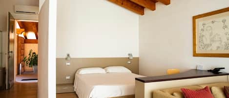 Un dormitorio con cama, lámparas de noche, un escritorio, una silla y un cuadro en la pared.