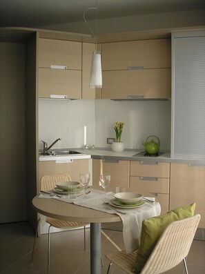 Une cuisine moderne avec un coin repas, comprenant une table ronde, des chaises, une bouilloire et un vase avec des fleurs.
