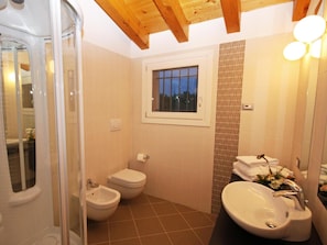 Une salle de bain équipée d’une douche, de toilettes, d’un bidet et d’un lavabo.