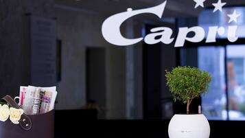 A reception desk with a sign reading 'Capri' and a potted plant.