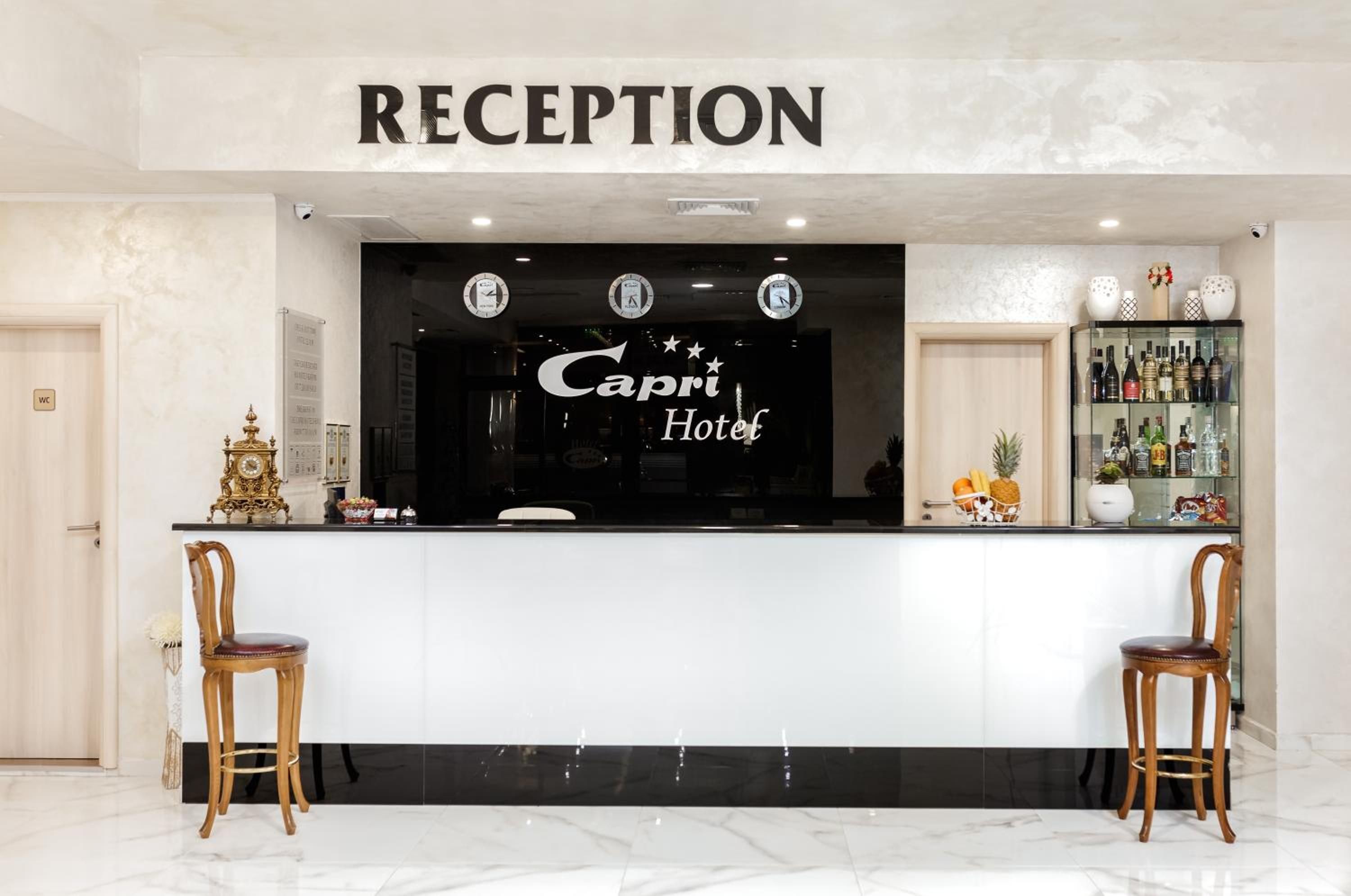 A reception area with a marble floor, two wooden chairs, a reception desk, and a clock above the desk.