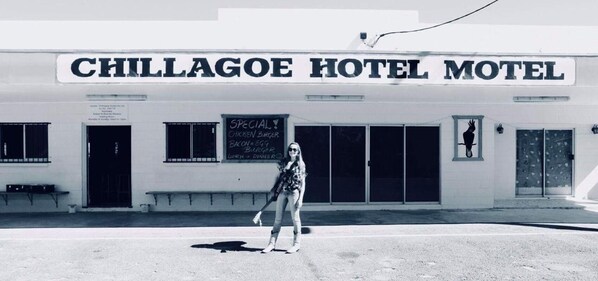 Un edificio con un letrero que dice 'CHILLAGOE HOTEL MOTEL' y una pizarra que anuncia 'HAMBÚRGERA DE POLLO ESPECIAL, TOCINO, HAMBÚRGER DE HUEVO, ALMUERZO Y CENA'.