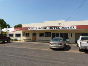 Un edificio con un cartel que dice 'CHILLAGOE HOTEL MOTEL' y un estacionamiento con coches.