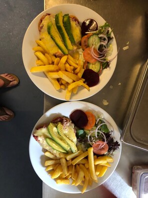 Dos platos de comida con papas fritas, rebanadas de aguacate y ensalada.