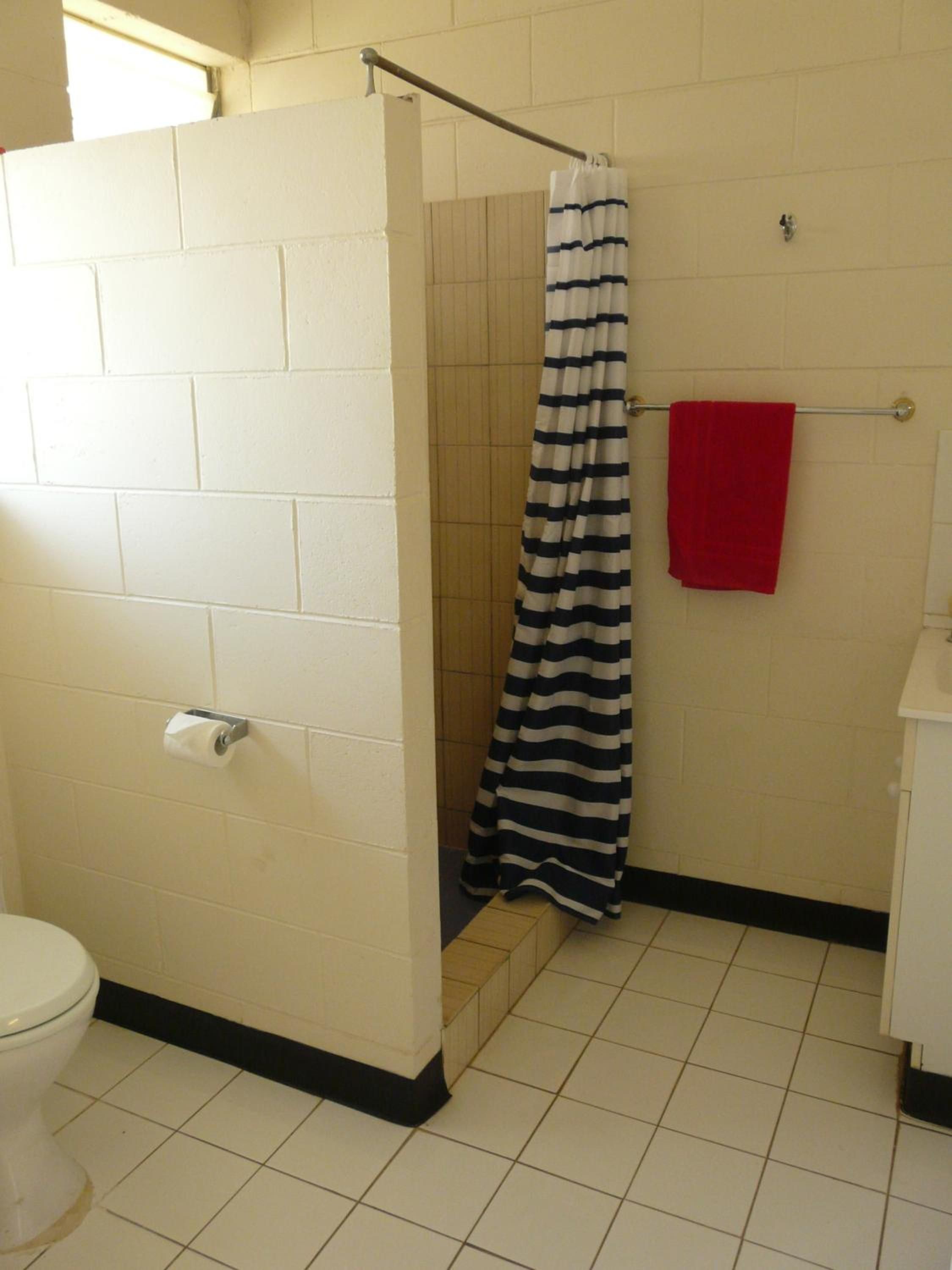 A bathroom with a shower, a toilet, and a towel rack.