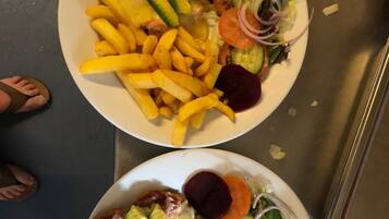 Dos platos de comida con papas fritas, rebanadas de aguacate y ensalada.