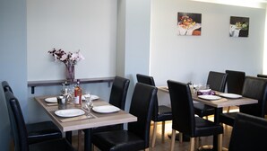 Un comedor con dos mesas, sillas negras y un florero con flores.