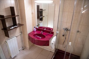 Un baño con un lavabo rojo, un espejo, una ducha y un perchero para toallas.
