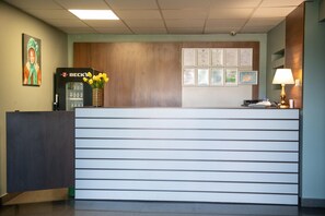 En receptionsdisk med en træpanelfond, et Beck's køleskab og en vase med gule blomster.
