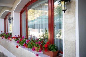 Fachada de edificio con ventanas de arco y balcones con flores rojas y rosas.