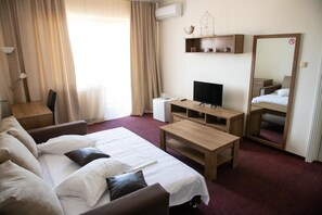 A hotel room with a bed, a desk, a television, and a mirror.