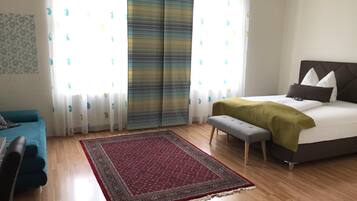 Ein Schlafzimmer mit einem Bett, einer Bank, einer Couch und einem gemusterten Teppich.
