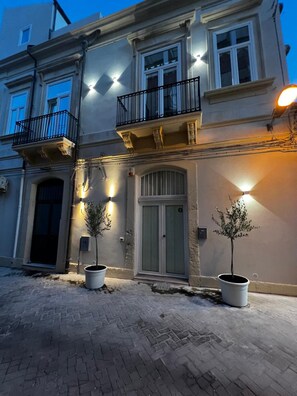 Un edificio de dos pisos con un balcón, una puerta y dos macetas.
