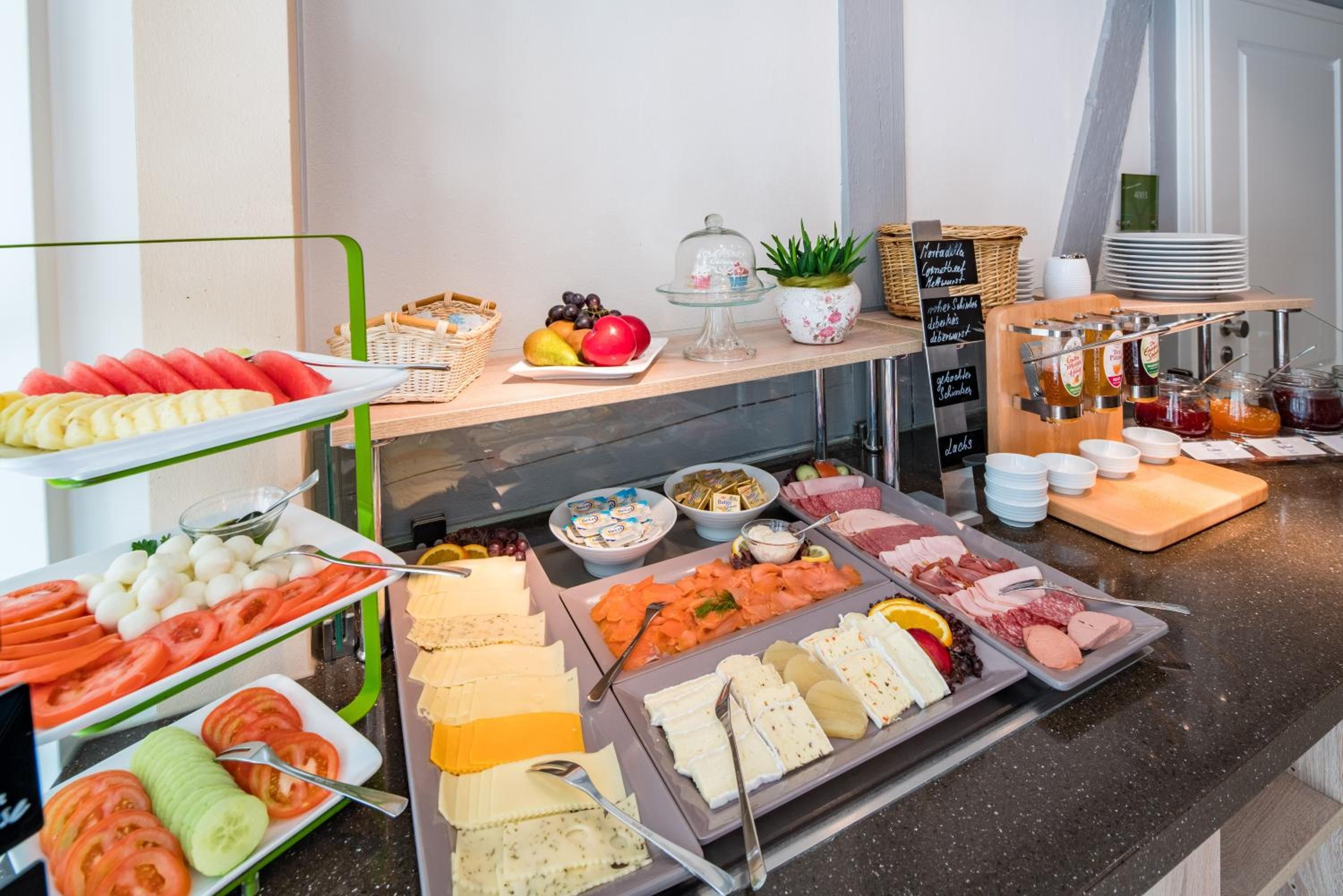 Ein Buffet mit einer Auswahl an Speisen, darunter Früchte, Käse, Fleisch und Soßen.