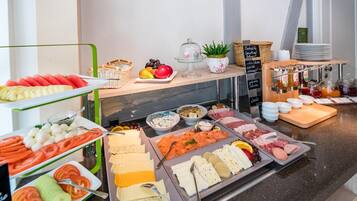 Ein Buffet mit einer Auswahl an Speisen, darunter Früchte, Käse, Fleisch und Soßen.