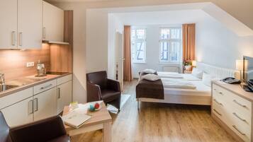 Ein modernes Hotelzimmer mit einer Küchenzeile, einem Bett, einem Schreibtisch und einem Stuhl.