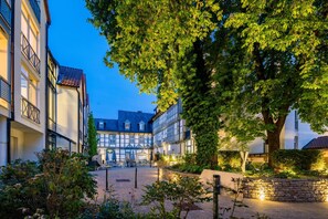 Une cour dotée d’une architecture européenne traditionnelle, avec notamment des bâtiments à colombages et un grand arbre qui offre de l’ombre.
