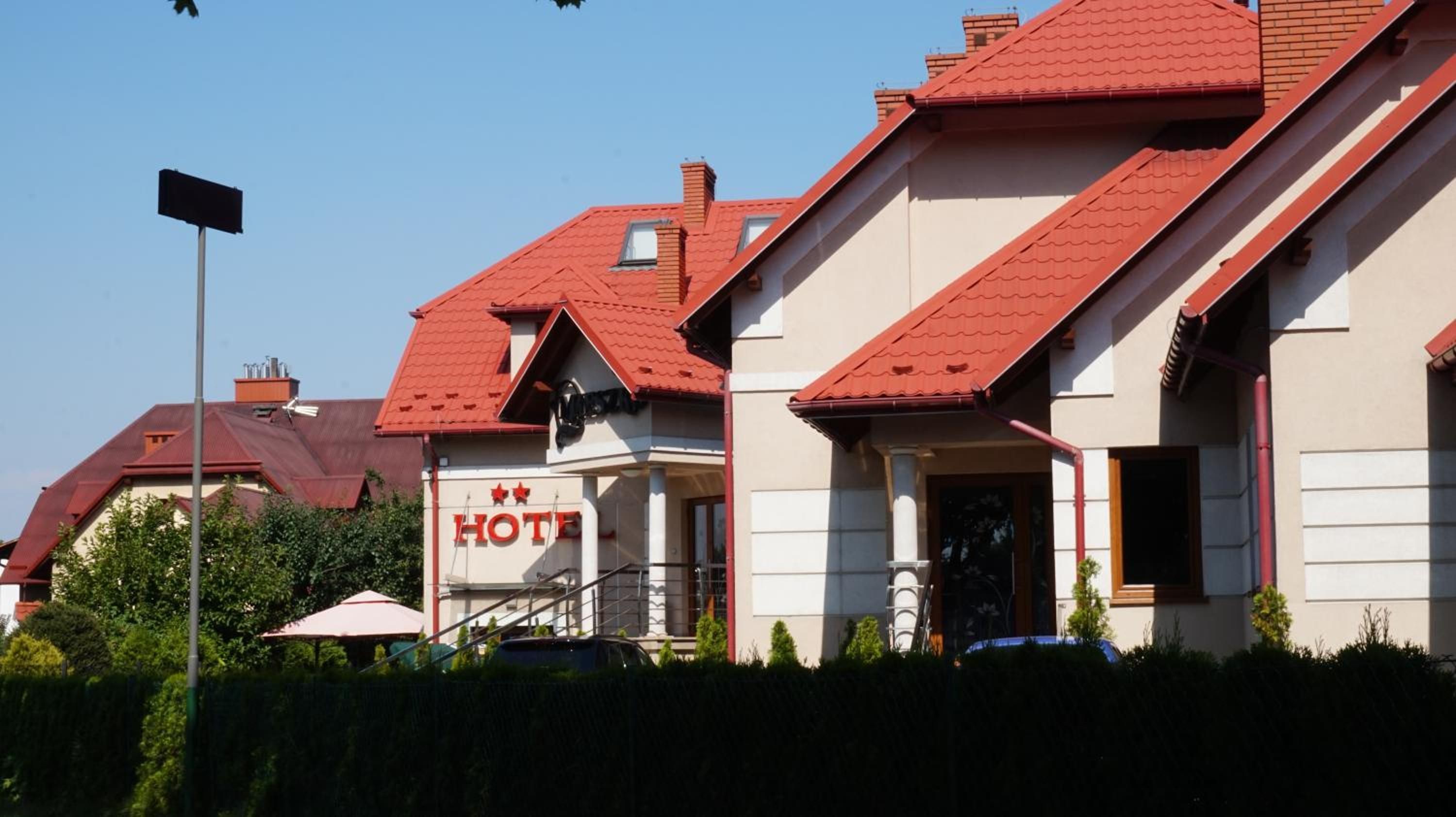 A hotel with a red roof, a signboard, and a staircase leading to the entrance.