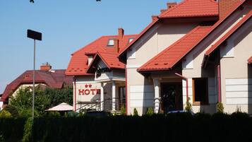 A hotel with a red roof, a signboard, and a staircase leading to the entrance.