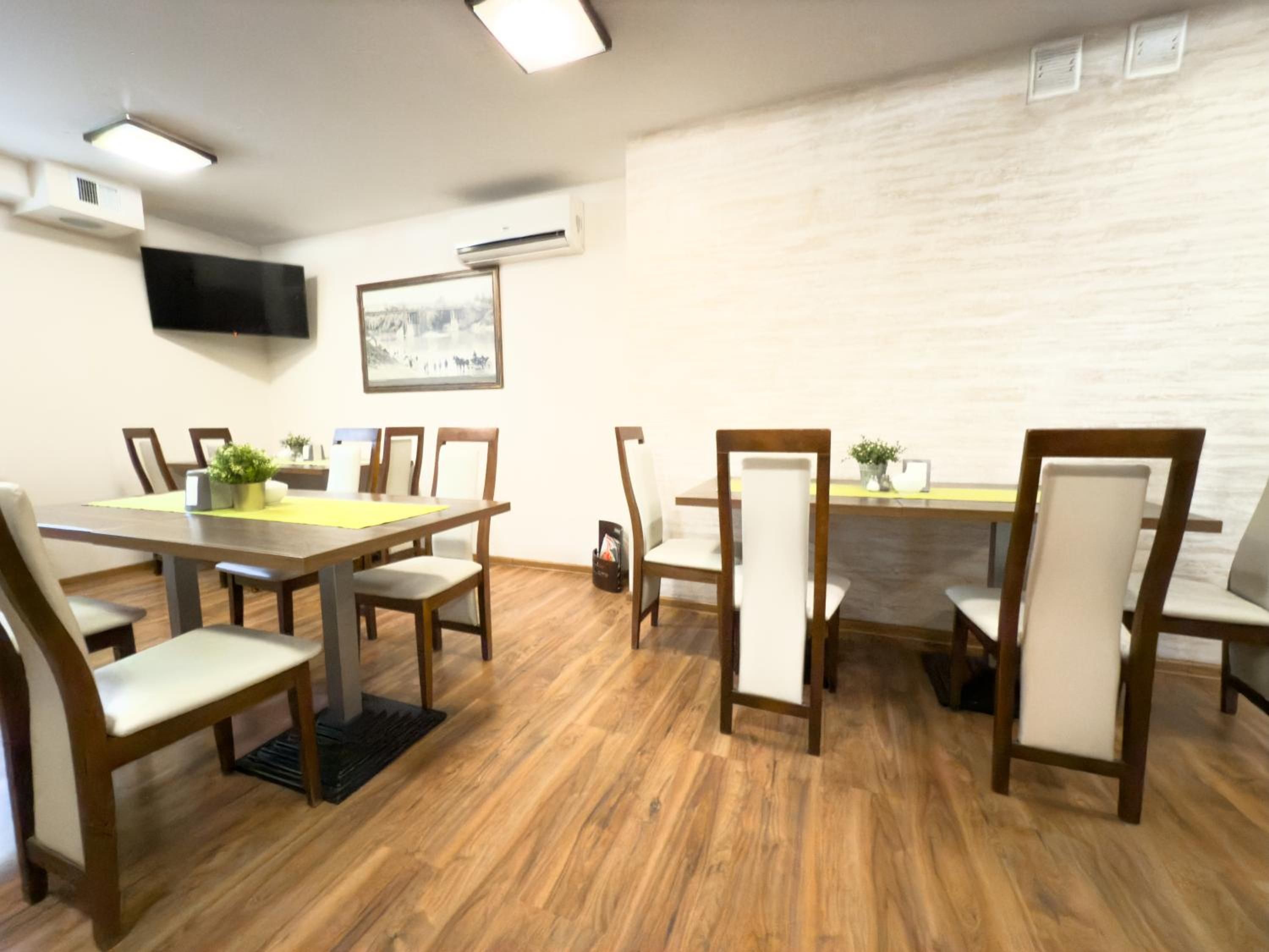 A conference room with a long table, chairs, a flat-screen TV, an air conditioner, and a framed picture on the wall.