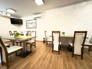 Una sala de conferencias con una larga mesa, sillas, un televisor de pantalla plana, un aire acondicionado y un cuadro en la pared.