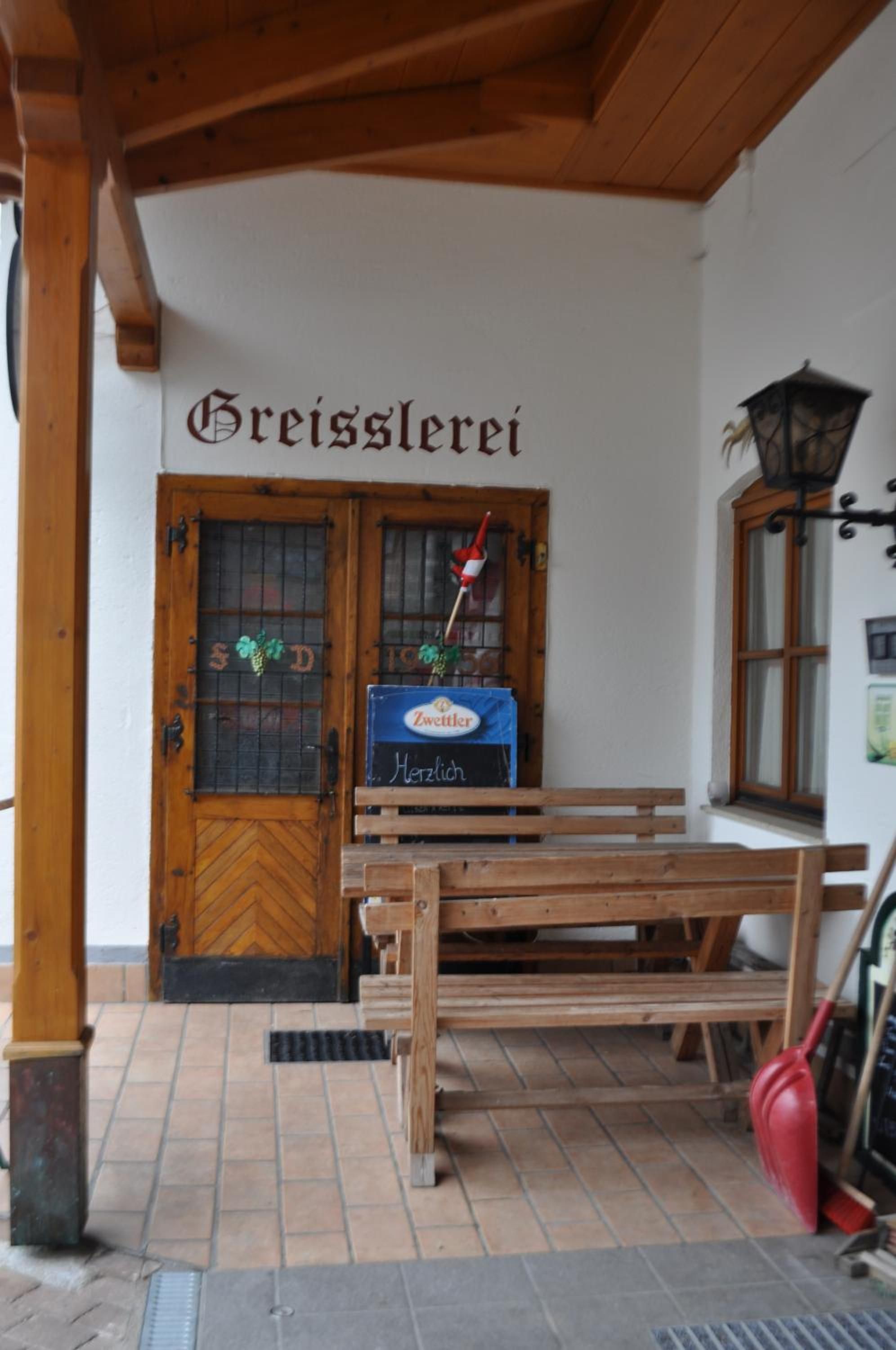 A wooden bench outside a building with a sign reading 'Breisslerei'.