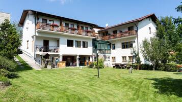 A two-story building with balconies, a covered outdoor seating area, and a well-maintained lawn.