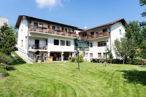 A two-story building with balconies, a covered outdoor seating area, and a well-maintained lawn. - Gasthof Diewald (Raach am Hochgebirge)