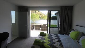 A hotel room with a bed, a chair, and a view of a lake and hills.