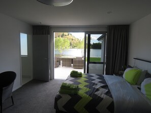 A hotel room with a bed, a chair, and a view of a lake and hills. - Cromwell Escape (Lowburn)