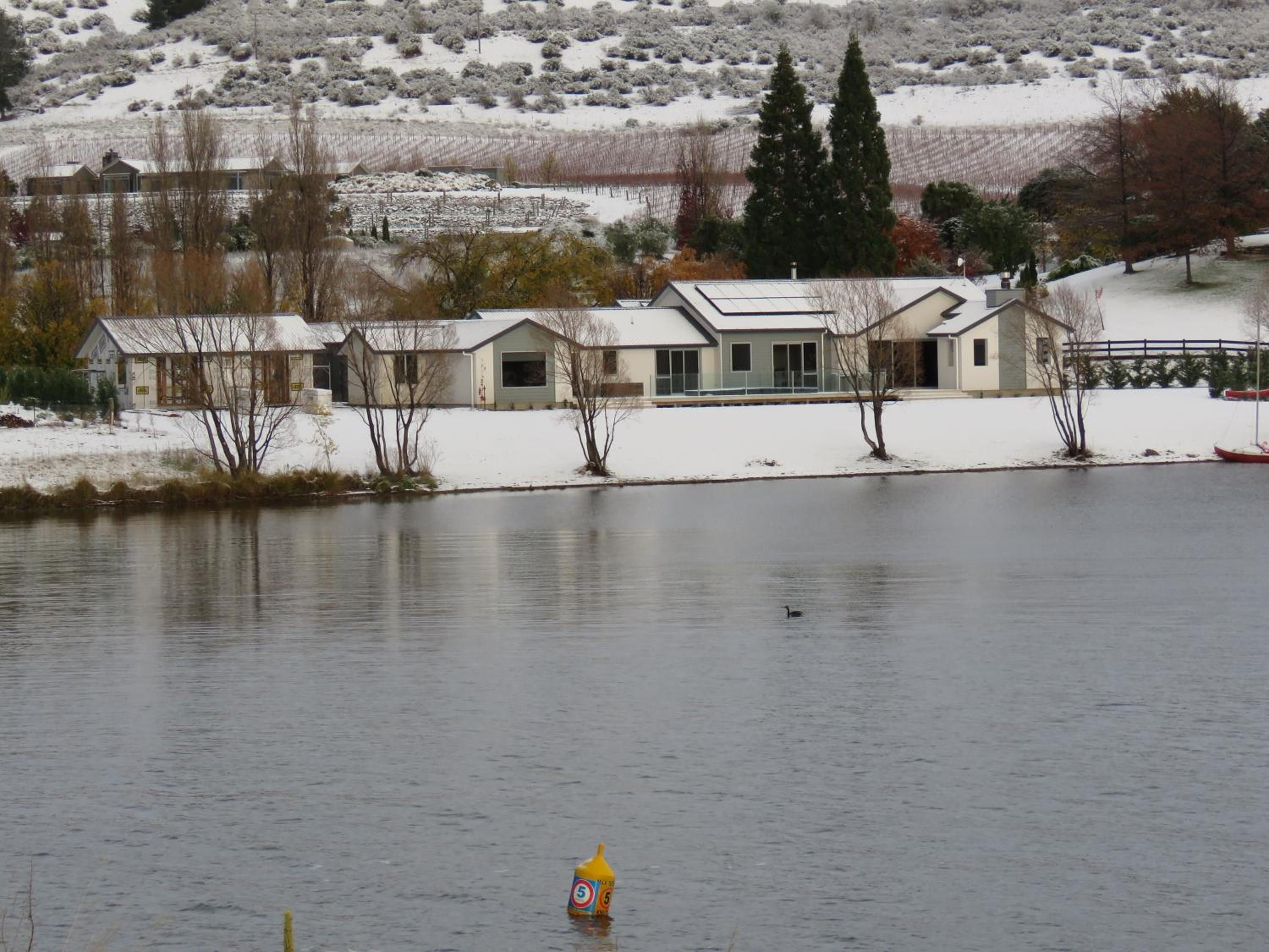 A lakeside property with multiple buildings, a dock, and a snowy landscape.