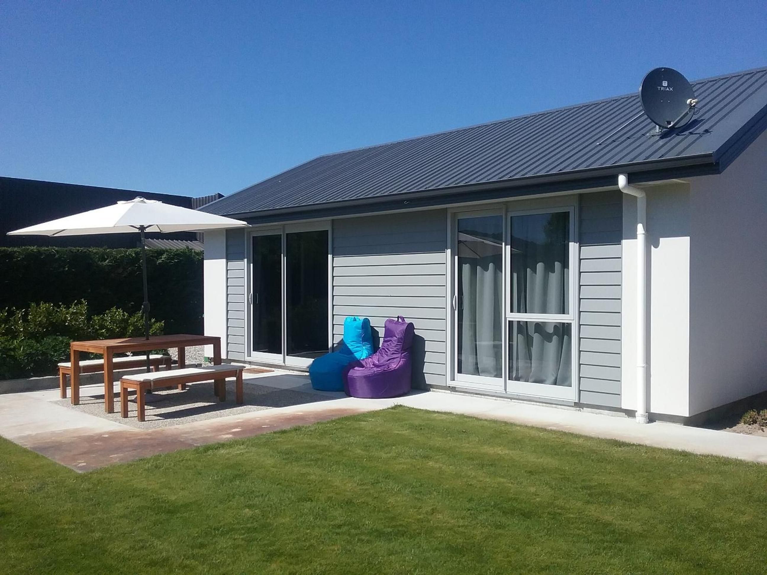 A modern house with a patio, a table, and two bean bags.