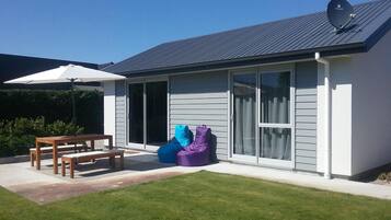 A modern house with a patio, a table, and two bean bags.