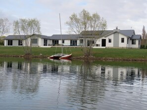 A lakeside property with a house, a dock, and a calm water body. - Cromwell Escape (Lowburn)
