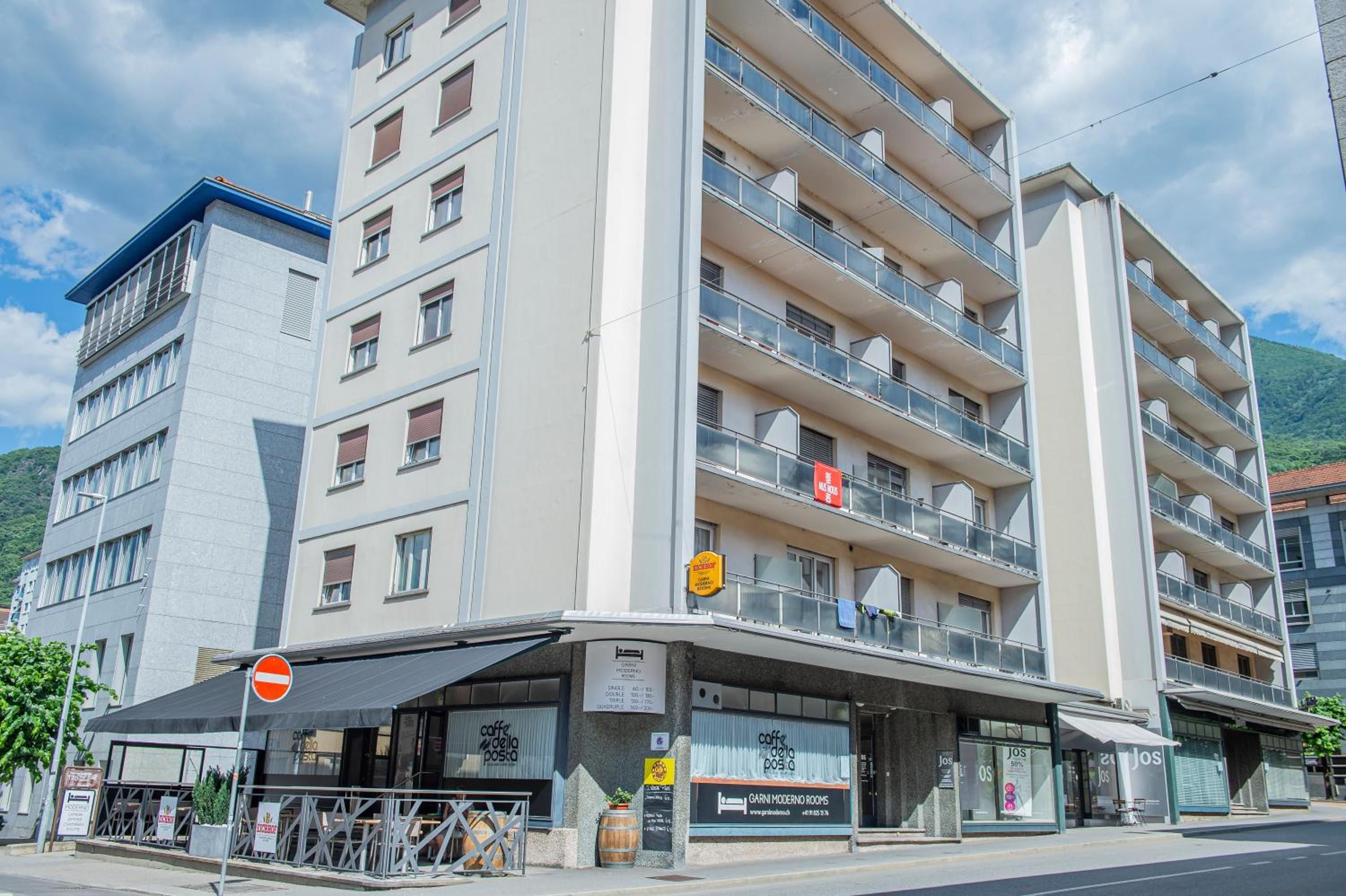 Ein mehrstöckiges Hotel mit Balkonen, ein Café im Erdgeschoss und ein Schild für Garni Moderno Rooms.