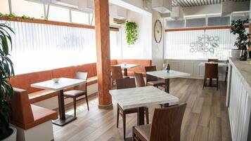 A modern restaurant interior with wooden flooring, marble tables, and cushioned seating.