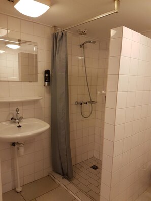A small bathroom with a sink, a shower, and a toilet. - Motel Oostvoorne (Oostvoorne)