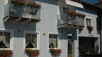 A building with multiple balconies, each adorned with flower boxes containing red and pink flowers.