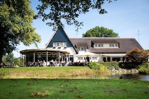 A traditional building with a curved structure, a pond, and a grassy area. - Hotel Restaurant Het Witte Huis (Olterterp)